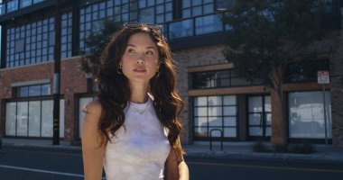 Şık bir kadın şehir mimarisini yürürken izliyor. Asyalı kız şehir caddesinde yürüyor.