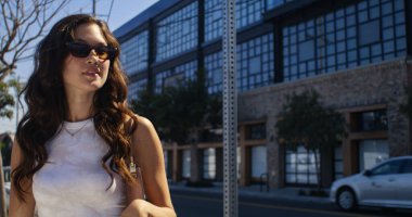 Rahat bir kadın modern binaların yanında buluşuyor. Asyalı kadın buluşmaya gidiyor.