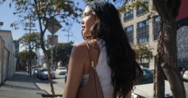 Şehir yolunda tek başına yürüyen arkadan gören kız. Asyalı kadın kaldırıma çıkıyor..