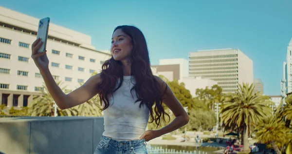 Menina sorridente posando no close-up da câmera. Mulher asiática fazendo selfie na paisagem urbana. — Fotografia de Stock