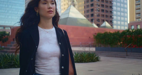 Gülümseyen kız sokakta yürürken rahatlıyor. Asyalı kadın şehir manzarasını izlemekten hoşlanıyor — Stok fotoğraf