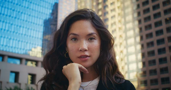 Carina donna sorridente sulla macchina fotografica all'aperto. Modello asiatico in posa di fronte a edifici. — Foto Stock