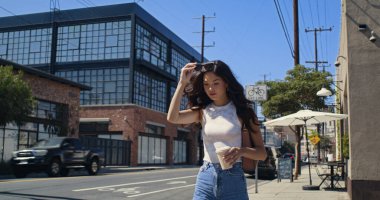 Kız sokakta yürürken yakın plan kahve içmekten hoşlanıyor. Asyalı kadın bardağı kaldırımda tutuyor..