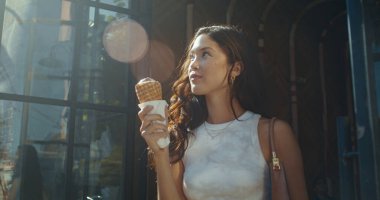 Gülümseyen kadın dışarıda dondurma yiyor. Esmer Asyalı kadın tatlı yiyor..