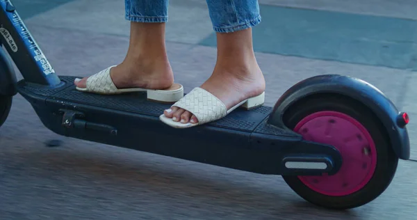 Donna sconosciuta piedi su scooter da vicino. Cavalletto gambe femminili su bici elettrica. — Foto Stock