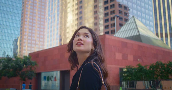 브루넷 여성은 도시 경관을 탐험하고 있습니다. 높은 건물 위를 올려다보고 있는 아시아 소녀. — 스톡 사진