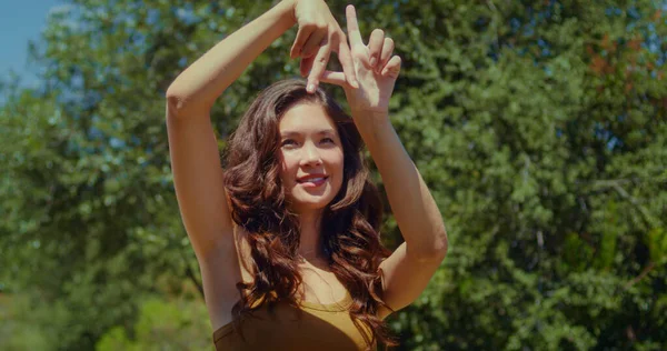 Женщина показывает знак Лос-Анджелеса пальцами в парке. Азиатская девушка делает жест название города — стоковое фото