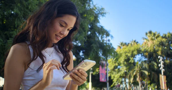 아시아인 여자가 스마트폰으로 사진을 스크롤하고 있습니다. 전화 화면을 보고 있는 웃는 여자 — 스톡 사진