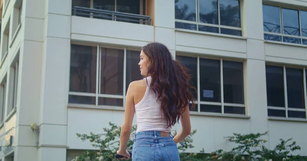 Jovem morena passeio de scooter na rua vista traseira. Menina asiática conduzir bicicleta elétrica. — Fotografia de Stock