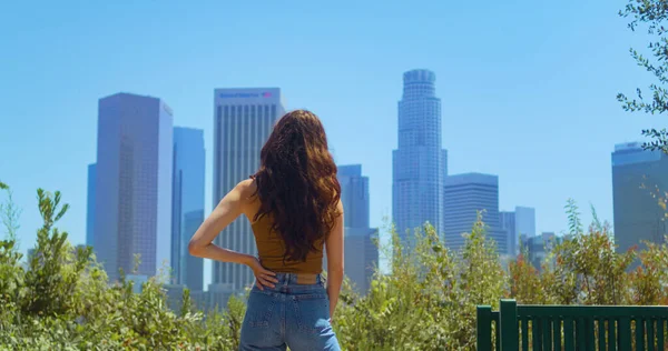 Bilinmeyen esmer, bulanık şehir manzarası. Genç bir kadın halk bahçesinde duruyor. — Stok fotoğraf