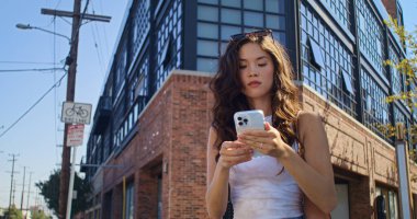 İş kadını yaya geçidine yürüyor ve mesaj okuyor. Asyalı kadın buluşmak için acele ediyor.