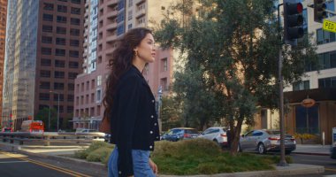 Yolun karşısına geçen neşeli kız. Asyalı kadın caddeden karşıya bakıyor..