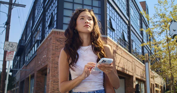 Νεαρή γυναίκα χρησιμοποιεί smartphone στέκεται σε σταυροδρόμι. Ασιάτισσα που κοιτάει στο τηλέφωνο. — Φωτογραφία Αρχείου