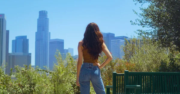 Mulher de pé no parque desfrutar de arranha-céus vista. Menina assistir paisagem urbana turva — Fotografia de Stock