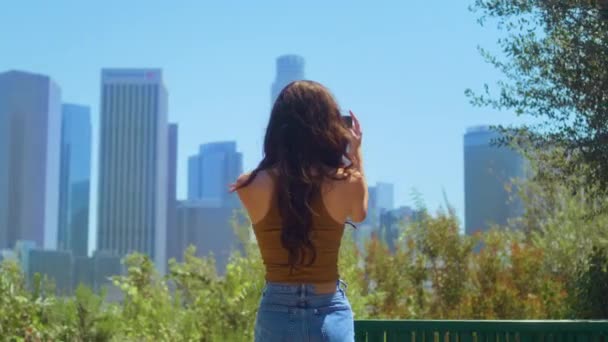 Powrót widok brunetka turysta co wideo cityscape stoi w zielony park. — Wideo stockowe