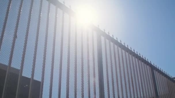 日光の下の景色の近代的な都市のフェンス。都市を背景にした金属バリア — ストック動画