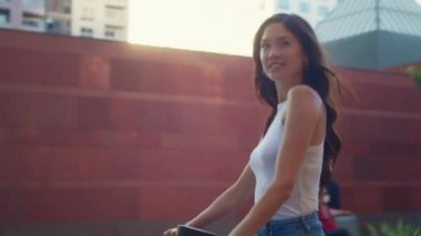Gülümseyen Asyalı kız yolda scooter kullanıyor. Şehir hayatında ekolojik ulaşım.