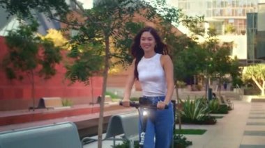 Asyalı kadın dışarıda elektrikli bisiklet kullanıyor. Modern şehirde mobiletle hızlı sürüş.. 