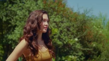 Yeşil Park 'ta poz veren sevimli bir kız. Dışarıda güneş ışığında duran Asyalı kadın.