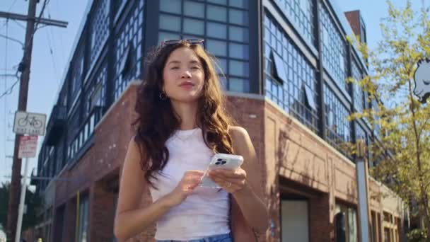 Asiatisk tjej viftar med handen till någon på gatan närbild. Kvinna möter vänner på promenad. — Stockvideo