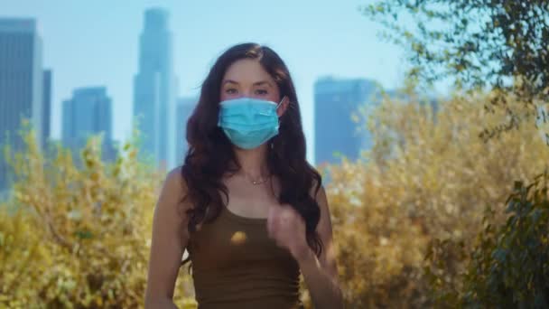 브루넷은 공원에서 마스크를 벗었다. 아시아 소녀는 자연에서 자유롭게 호흡 한다. — 비디오