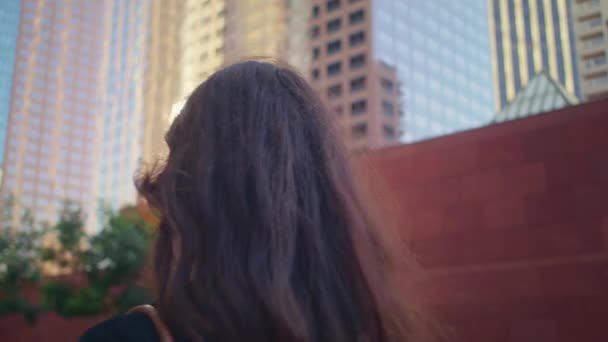 귀여운 여자 가 도시 건물을 뒤돌아보고 있습니다. 일광욕을 즐기는 아시아 소녀. — 비디오