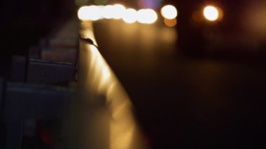 Gece karayolu bariyerleri, araba ışınlarını yakından yansıtıyor. Akşam trafik ışıkları