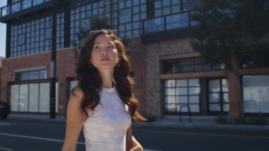 Şık bir kadın şehir mimarisini yürürken izliyor. Asyalı kız şehir caddesinde yürüyor.