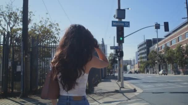 Mujer irreconocible cruzando la calle. Vista posterior joven chica va en crosswalk. — Vídeos de Stock