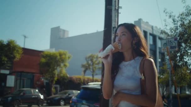 Muchacha atractiva degustación de helado que va por la calle. Mujer asiática lamiendo postre — Vídeos de Stock