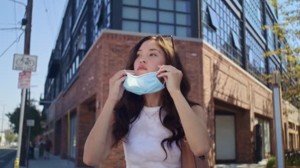 Menina bonita colocando máscara na rua. Atraente asiático mulher uso rosto proteção — Vídeo de Stock