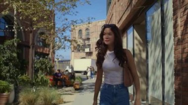 Şehir caddesini keşfeden muhteşem bir kız. Yeşil bölgede yürüyen esmer turist.