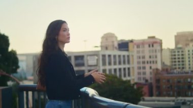 Asyalı kız şehir manzarasını seyrediyor. Sakin kadın, parmaklıkların yanında dur..