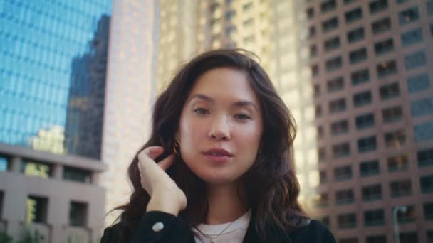 Nette Frau, die draußen vor der Kamera lächelt. Asiatisches Model posiert vor Gebäuden. — Stockvideo