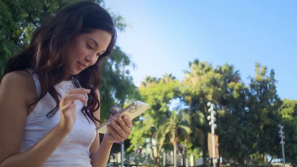 Azjatka przewijająca zdjęcie na smartfonie. Śmiejąca się kobieta na ekranie telefonu — Wideo stockowe