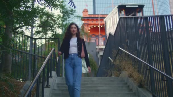 Meisje loopt het stadspark af. zelfverzekerde aziatische vrouw gaan op ladder buiten. — Stockvideo