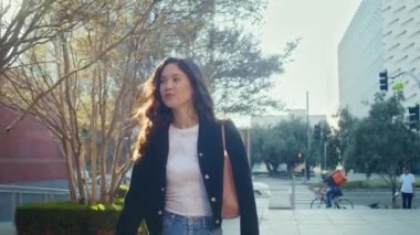 Sokakta gün ışığında gülümseyen yürüyen kız. Asyalı esmer şehir manzarasını seviyor.