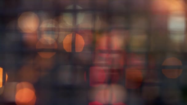 Blurred bokeh lights moving blinking at squared metallic mesh netting fence. — Stock Video