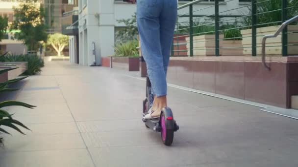 Joven morena paseo scooter en la calle vista trasera. Chica asiática conducir bicicleta eléctrica. — Vídeos de Stock