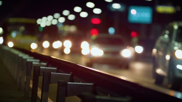 Barandilla de la autopista de la ciudad en primer plano de la noche. Coches siluetas que conducen por carretera. — Vídeo de stock