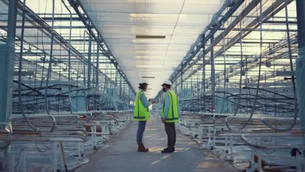 Två fabriksarbetare anordning som visar nya säkerhetsdata ingenjörer diskuterar — Stockvideo