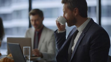 Gülümseyen yönetici bilgisayarını daktilo ediyor birlikte çalıştığı kafede kahve içiyor..