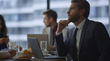 Kafe ofisinde iş arkadaşıyla birlikte çalışan düşünceli bir girişimci..