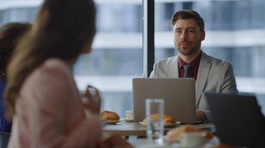 İş arkadaşları ofisteki dizüstü bilgisayarda çalışan kafe hakkında konuşuyor..