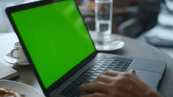 Człowiek ręce wpisując klawiatury laptop zielony ekran w kawiarni stół restauracja. — Zdjęcie stockowe