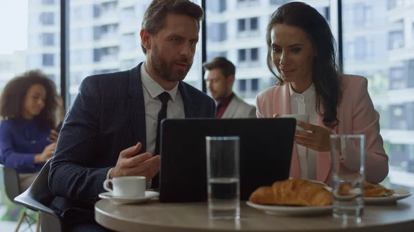 Fokuserte forretningsfolk som diskuterer markedsføring ved hjelp av bærbar datamaskin på kafe. – stockfoto