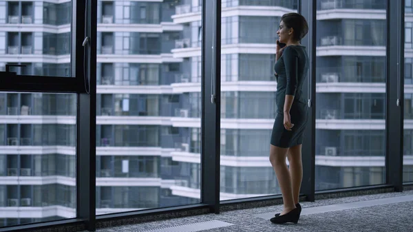 Mulher de negócios chamando smartphone falando colega na janela do edifício corporativo — Fotografia de Stock