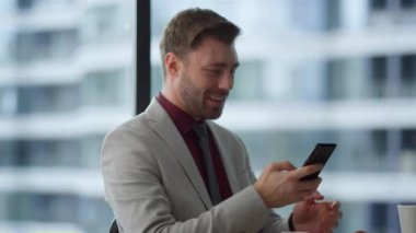 Çeşitli takım yöneticileri birlikte çalışarak kafede cep telefonundan iyi haberler okuyorlar.