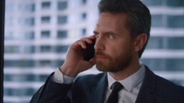 Ciddi bir yetişkin işadamı modern ofiste telefonla konuşuyor..
