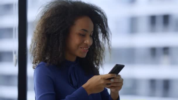 興奮したアフリカ系アメリカ人女性はスマートフォンで良いニュースの仕事のプロモーションを祝う. — ストック動画